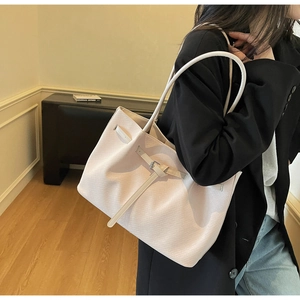 Detailed macro view of woven texture and long shoulder strap on cream large tote bag