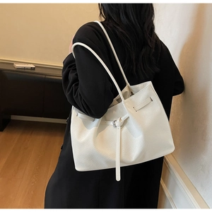 Detail view of large white woven texture tote bag worn as an underarm shoulder bag