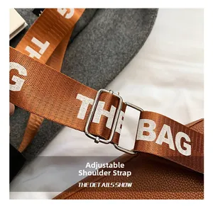 Detail of adjustable woven wide shoulder strap with white lettering and metal buckle