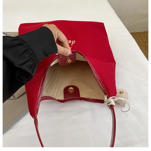 Detail of red canvas tote bag showing golden magnetic closure and inner beige lining
