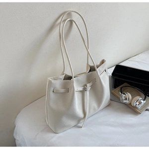 Chic cream woven tote bag with silver buckle detail next to laptop and headphones