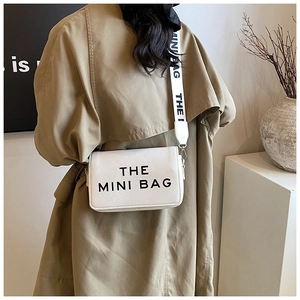 Detail view of white mini crossbody bag with textured faux leather and wide strap