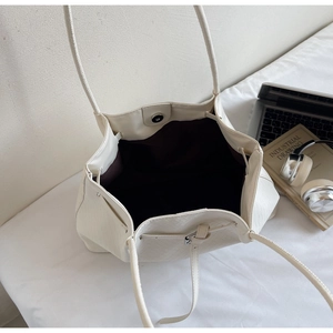 Détail du sac cabas tissé blanc montrant le fermoir magnétique et la doublure brune