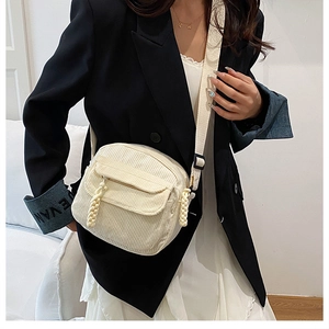 Detail of off-white corduroy crossbody bag with woven zipper pull and pocket structure