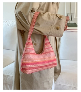 Close-up of a colorful woven hobo shoulder bag with gradient pink and orange stripes