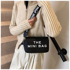 Detail of black mini crossbody bag featuring wide branded strap and white lettering
