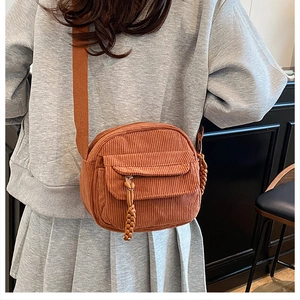 Close-up of caramel corduroy crossbody bag with ribbed texture and woven zipper detail