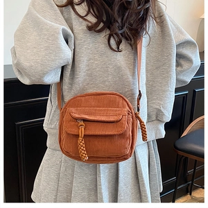 Detailed shot of caramel corduroy crossbody bag with woven knot zipper on a model