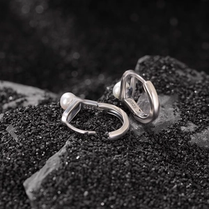 Minimalist S925 silver U-shaped oval earrings with white pearls on a textured black surface