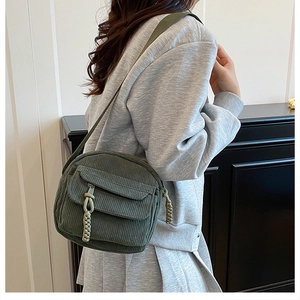 Detail of dark green corduroy crossbody bag with woven rope pull and textured fabric