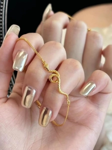 Detail of golden snake bracelet with scale texture and mirror reflection aesthetic