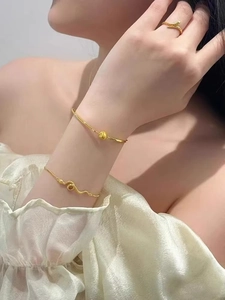 Close-up of elegant gold snake-shaped ring, bracelet and chain on woman wrist