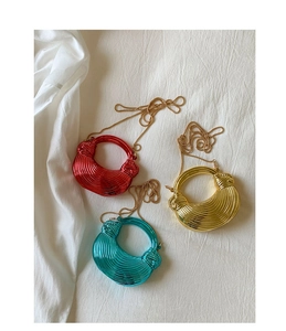 Detailed macro view of spiral textured metallic evening bags in red, gold, and teal colors