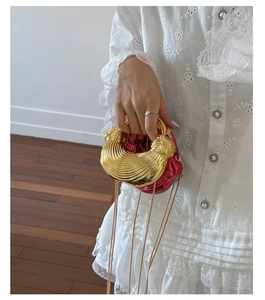 Close-up of fuchsia metallic evening clutch with wide gold knot handle and chain