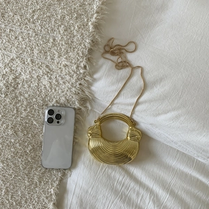 Detail of a mini gold crescent evening bag with ring handle and metal chain strap