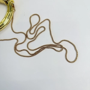 Detailed close-up of a glossy golden metal chain strap with polished circular link design