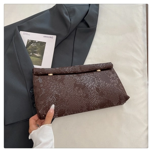 Macro view of brown snakeskin texture and golden cylindrical clasps on a stylish clutch bag