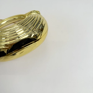 Detailed view of golden evening clutch featuring wave texture and round metal handle