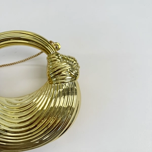Close-up of golden metallic half-moon bag with textured surface and knot clasp