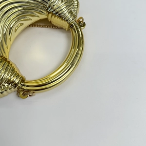 Macro shot of gold evening clutch featuring 3D embossed stripes and metal chain strap