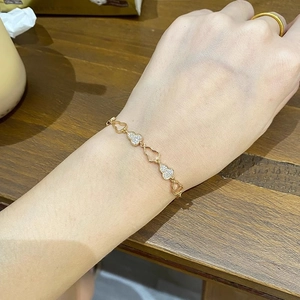 Gros plan d'un bracelet coeur en or champagne avec pierres pavées porté au poignet
