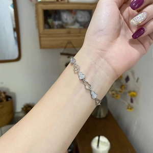Détail macro du bracelet hulu argenté avec zircons étincelants et breloques en cœur