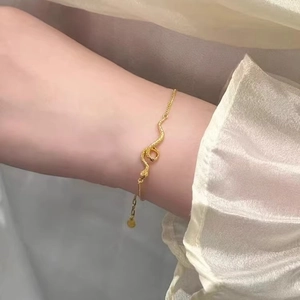 Elegant gold snake bracelet with fine chain and textured serpent design on silk background