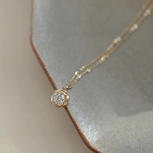 Collier élégant à pétales de rose dorés avec un oxyde de zirconium sur un plateau gris