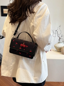 Borsa a tracolla nera alla moda con stampa a ciliegia e decoro di paillettes su modella