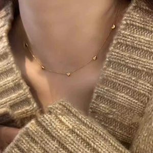Minimalistische gouden hartjesketting op een model met een comfortabele gebreide trui