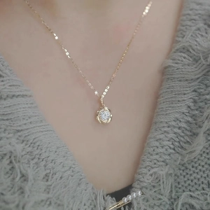 Gros plan d'un collier rose dorée avec pendentif diamant brillant sur un pull gris