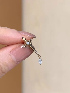 Macro shot of gold sword ear stud with zircon stones and a marquise pendant detail