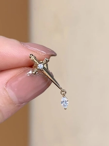 Macro detail of a vintage gold sword stud earring with sparkling crystal embellishments