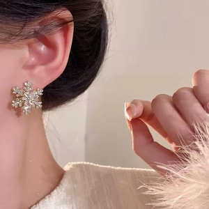 Sparkling snowflake stud earrings with crystals on female model for elegant winter look