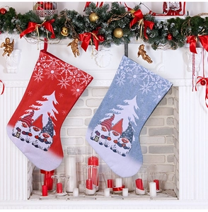 Close-up of hanging Christmas gnome stockings in red and grey-blue over a cozy fireplace