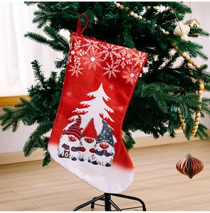 Detail of red Christmas stocking with Rudolf gnomes hanging on a festive decorated tree