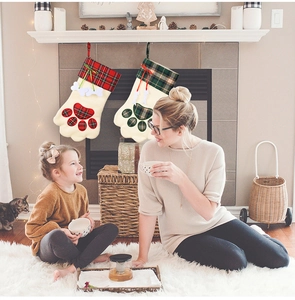 Weihnachtsstrümpfe für Haustiere mit Pfotenmuster hängen an einem festlichen Kamin Sims