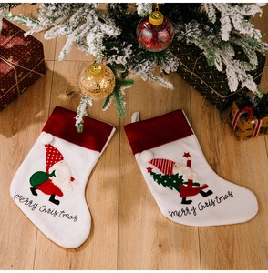 Detail of two Christmas stockings with 3D Santa embroidery on light wooden floor