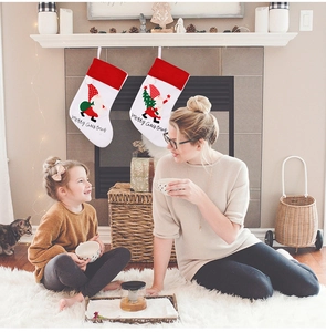 Detail of two Christmas stockings with embroidered Santa patterns hanging on a fireplace