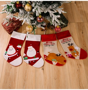 Set of four knitted Christmas stockings with Santa and reindeer motifs on wooden floor