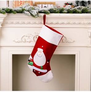 Detail of a red Christmas stocking with Santa Claus embroidery hanging on a white fireplace