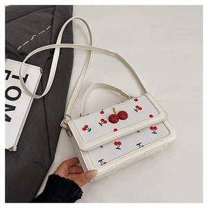 Detail of white leather cherry print crossbody bag with rhinestone cherry buckle and strap