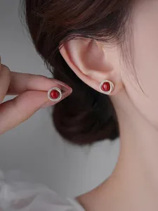 Dettaglio macro di orecchini a lobo cabochon rossi con contorno di zirconi