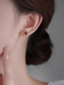 Primo piano di orecchini di perle rosse con halo di diamanti su una modella donna