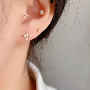Minimalist gold bee stud earring set with zircons shown on a female model ear