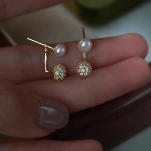 Detail of elegant gold-toned pearl earrings with micro-set zircon spherical charms