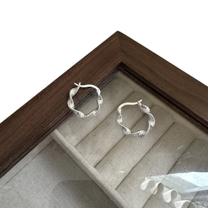 Elegant silver twisted Mobius hoop earrings displayed in a luxury wooden jewelry box