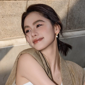 Elegant gold drop earrings with irregular pearls shown on a model in outdoor lighting