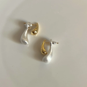 Detailed shot of asymmetrical teardrop earrings in matte silver and polished gold finish