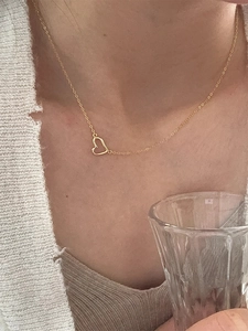 Primo piano della collana con ciondolo a cuore d'oro minimalista indossata sul collo per un look chic